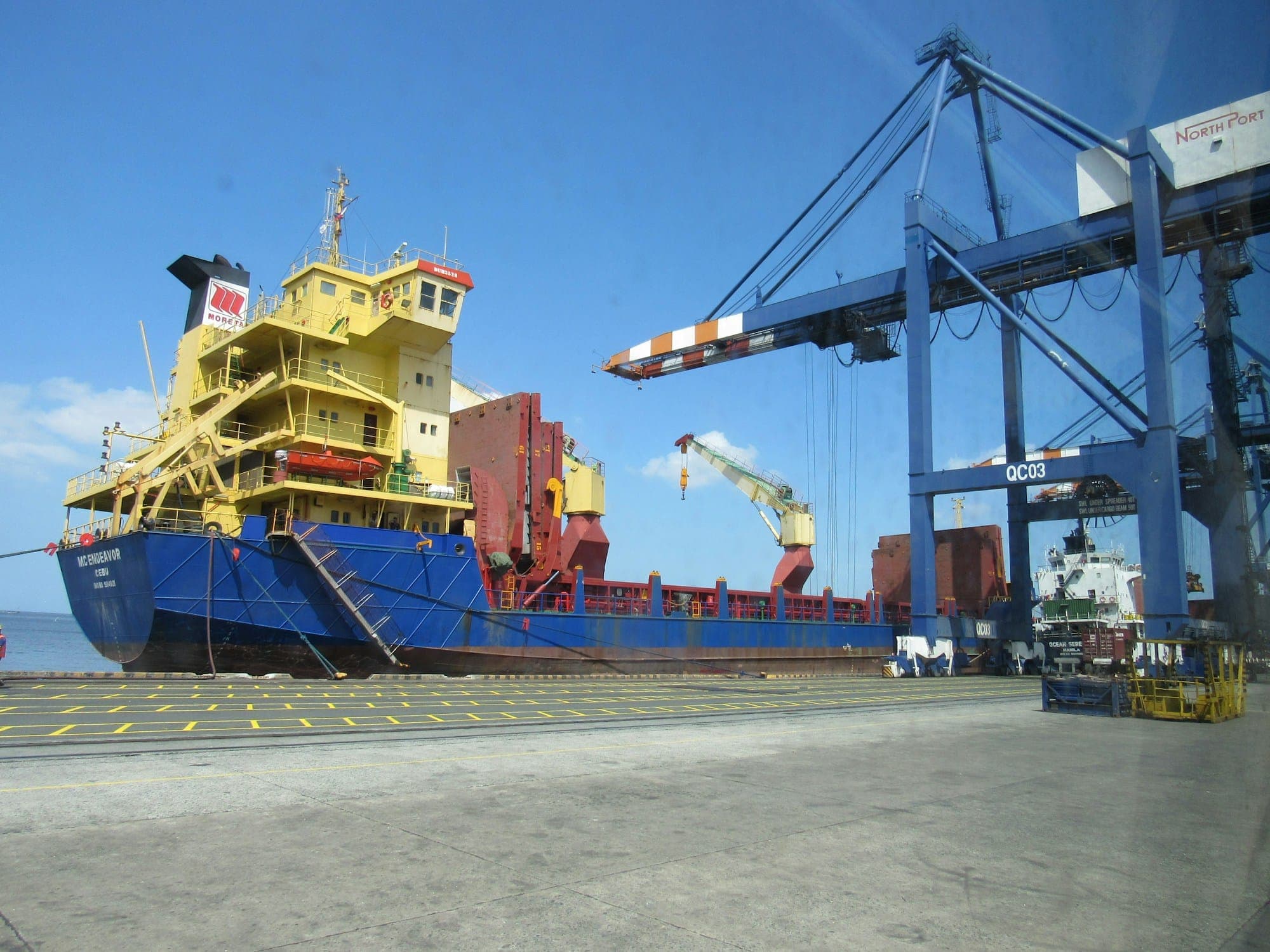 A cargo vessel alongside a berth with gantry cranes working the holds